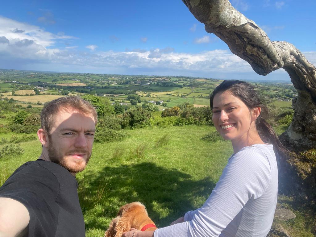 Hilltop selfie above green patchwork fields, dog in tow