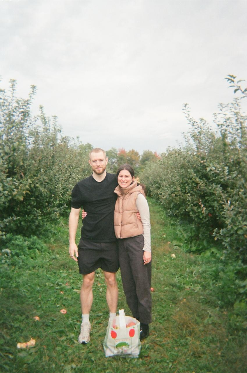 Olivia and Blaine arm in arm on an orchard path